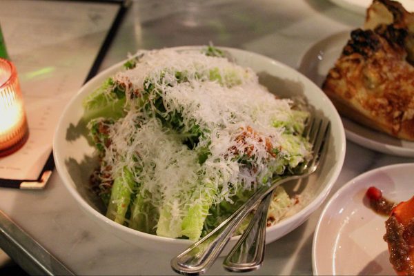 A caesar salad with white cheese and chunks of lettuce.