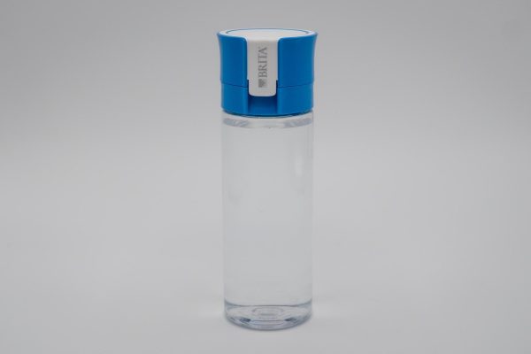 A clear water bottle with a blue and white lid with “BRITA” written on it, against a white background.