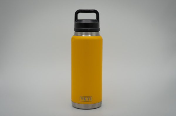A yellow water bottle with a black lid with the “YETI” logo against a white background.