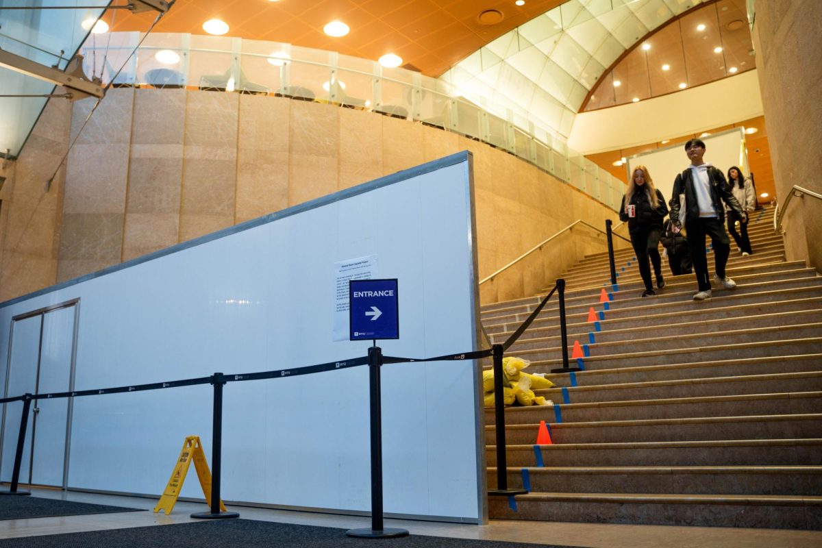 Three students walk down the Grand Staircase in the Kimmel Center for University Life. A barrier is placed on the left side of the staircase.