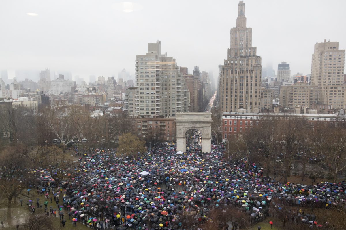 A bird’s eye view of Washington Square Park crowded with protestors holding umbrellas.