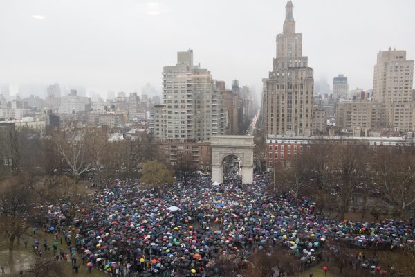 A bird’s eye view of Washington Square Park crowded with protestors holding umbrellas.