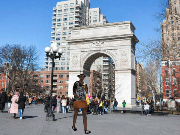 A person walking in Washington Square Park is wearing a brown mini skirt, black sneakers and a black open-knit sweater over a white tank top, while carrying a yellow tote bag.