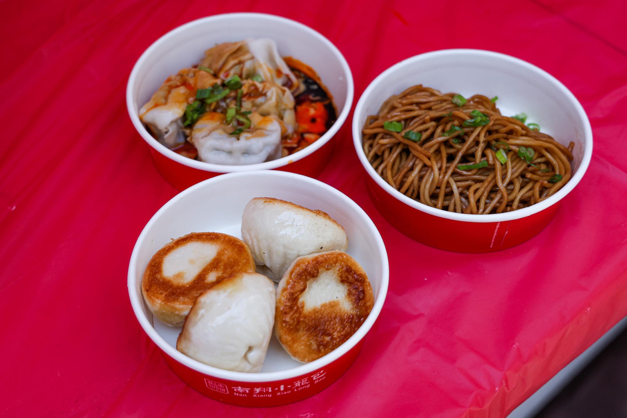 Three serving cups for festival guests with fried dumplings, soup dumplings and noodles.