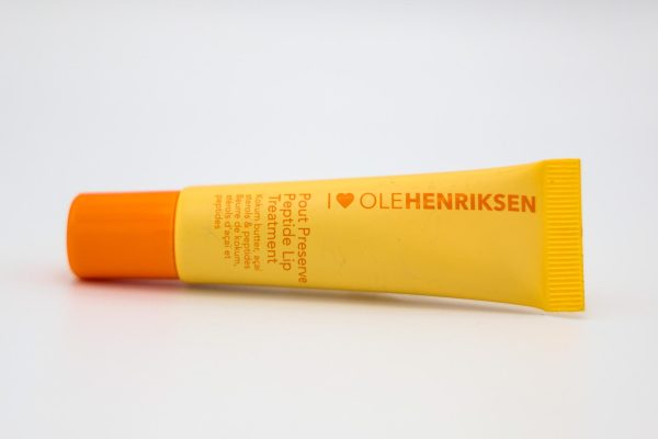 Yellow and orange tube of lip balm with the brand name "OLEHENRIKSEN" displayed horizontally. 