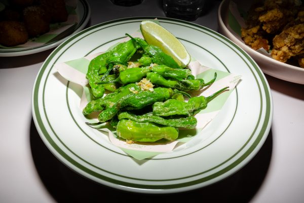 A plate of green peppers and a slice of lime.