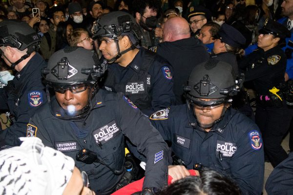 Police officers holding down protesters at night.