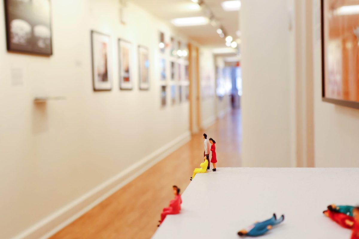 Three small figurines sit and stand near an edge, overlooking the a hallway with photos on the wall.