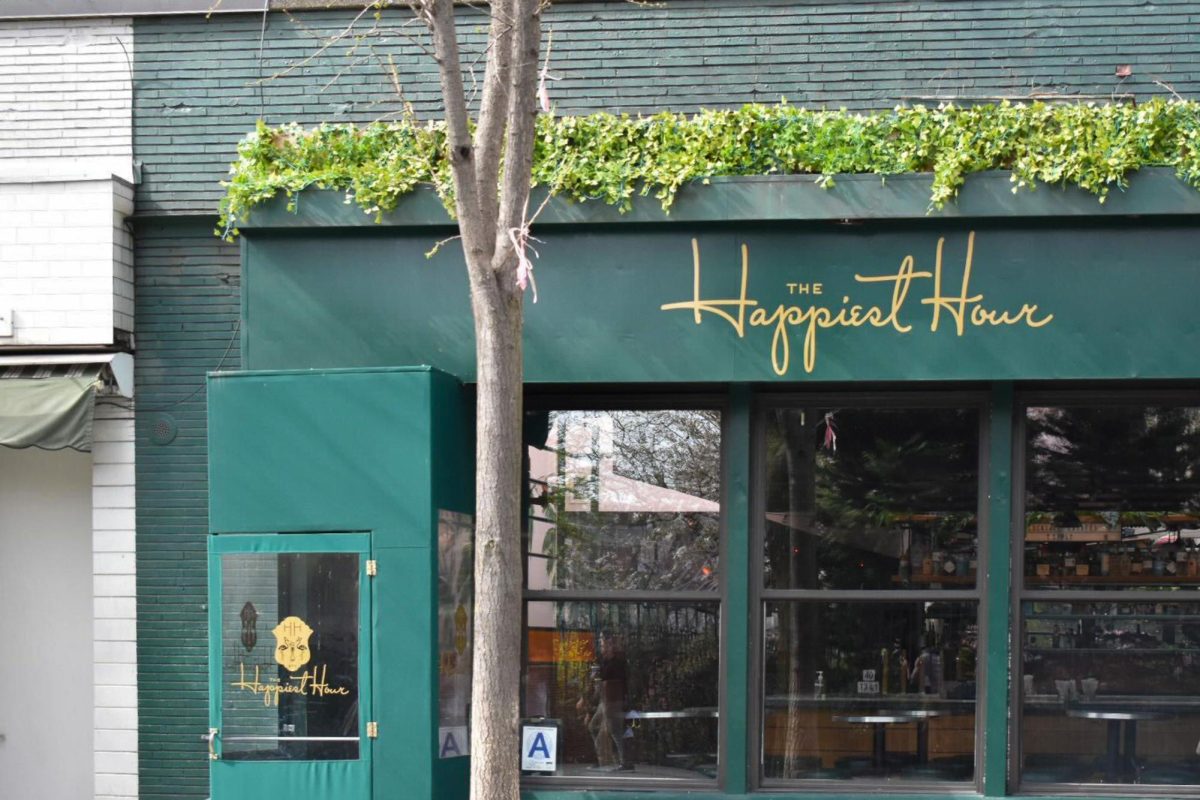 Front of the bar The Happiest Hour which has a green facade and gold lettering.