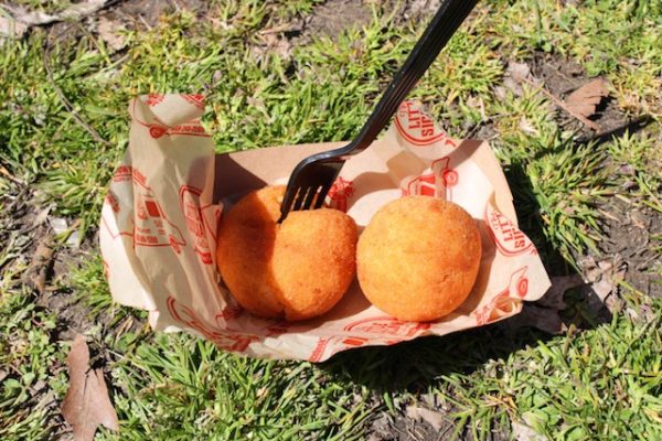 Two breaded balls in a cardboard tray on the grass. 
