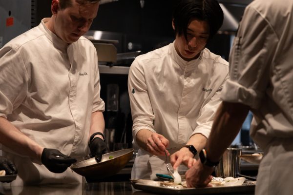 Three chefs prepare dishes in a kitchen.