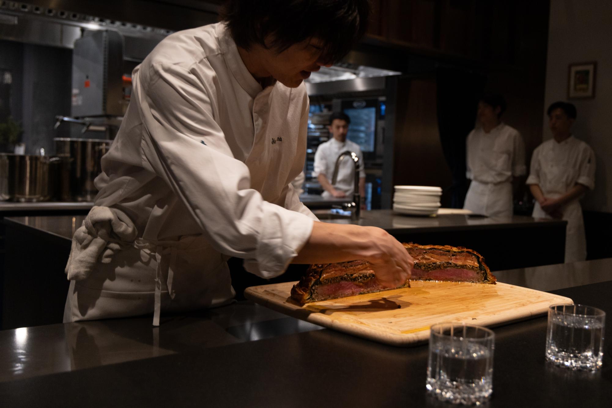 A chef shows the layers of a piece of meat.