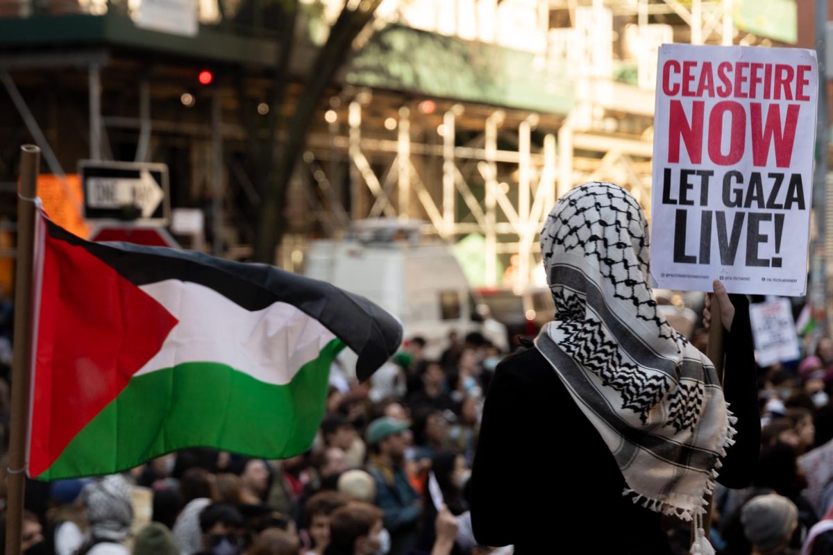 A woman holding a sign that reads “CEASEFIRE NOW LET GAZA LIVE!”