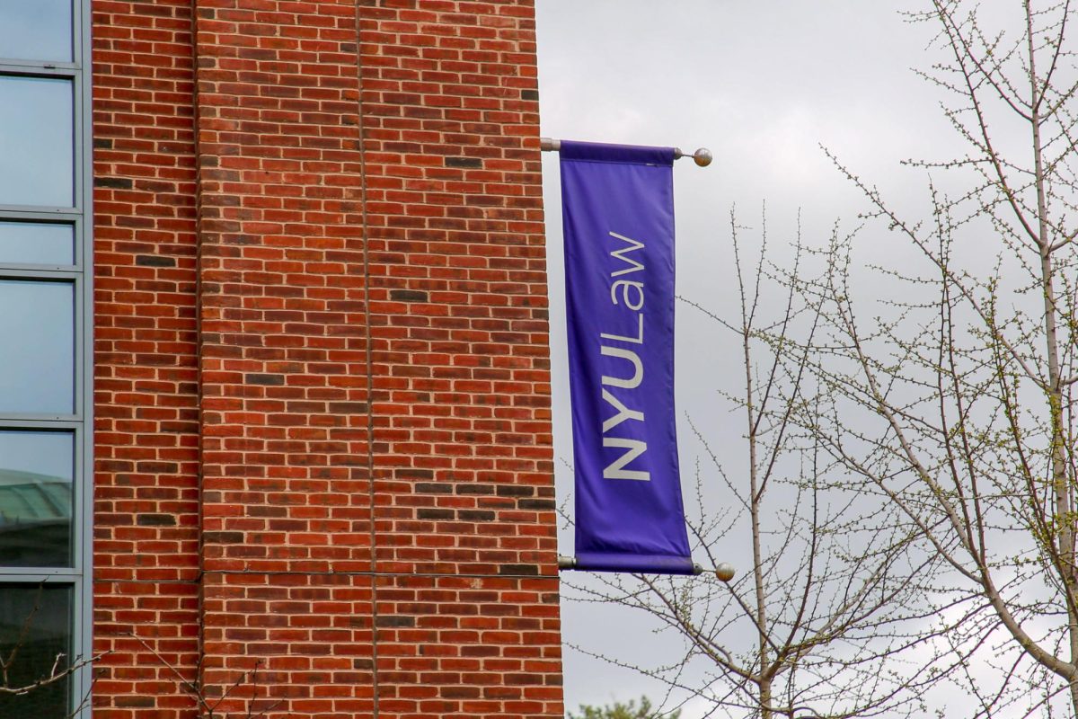 A photo of a building. A purple "N.Y.U. Law" flag is on the side of the building.