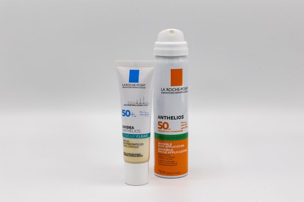 Two white La Roche-Posay sunscreen bottles. One bottle is a tube while the other is a cylinder spray.