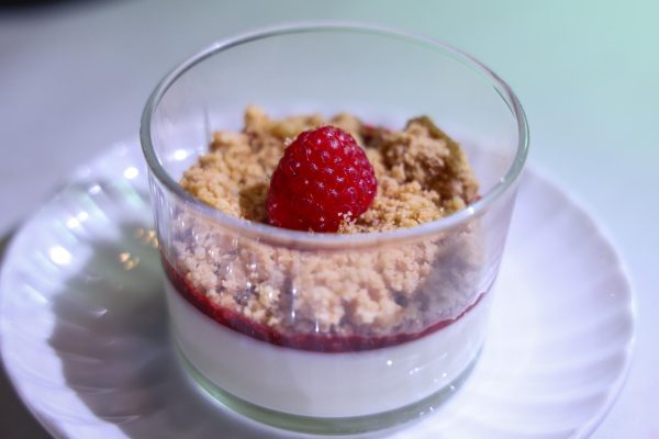 A raspberry sits atop layered butter crumble and vanilla yogurt.