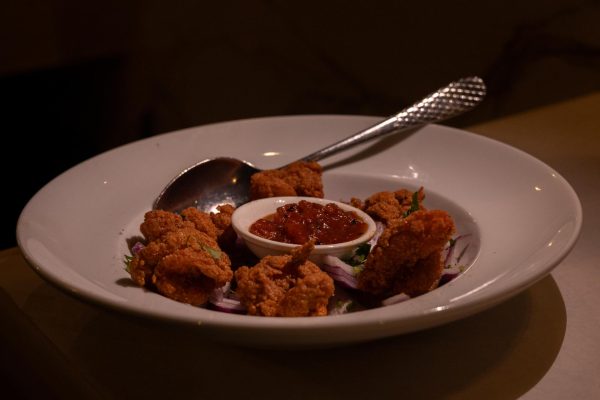 Fried shrimp on a raised plate served with dipping sauce and vegetables. 4: Chicken served on a skillet with mango and onion. 
