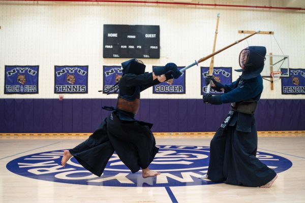 Two people in black garments fighting with wooden swords.