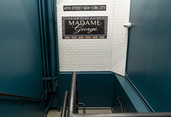 White tile and green entrance in the style of a subway with a blue sign that says “MADAME GEORGE” and above it “45TH STREET NEW YORK CITY.”  