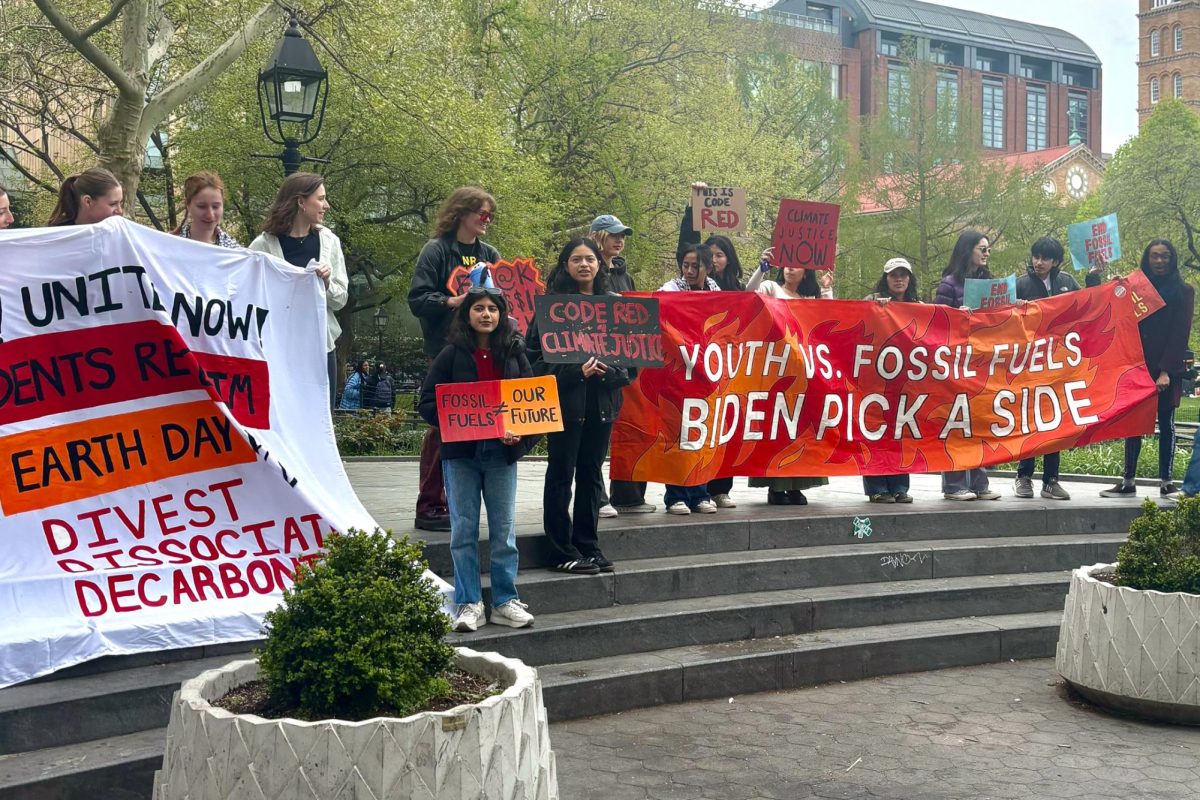 Students protesting in Washington Square Park holding signs that say “YOUTH VS. FOSSIL FUELS BIDEN PICK A SIDE,” “THIS IS CODE RED,” “END FOSSIL FUELS,” “CLIMATE JUSTICE NOW” and more.