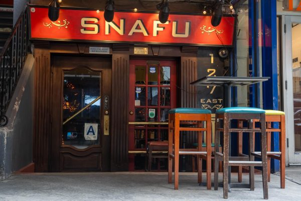 Wooden exterior of a bar with a red sign that says “SNAFU” in yellow font. 