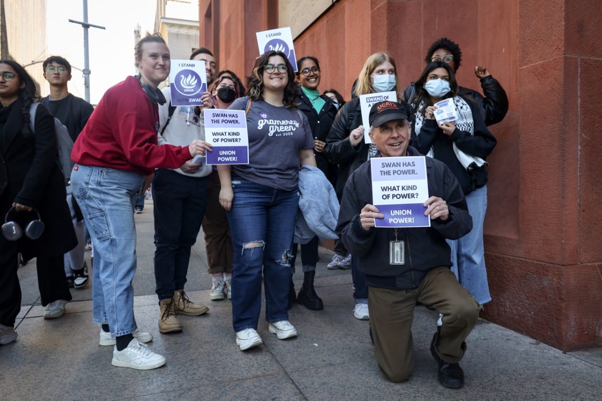 A+group+of+protesters+stand+in+front+of+Bobst+Library+holding+purple+signs+with+the+words+%E2%80%9CSWAN+HAS+THE+POWER.+WHAT+KIND+OF+POWER%3F+UNION+POWER%21%E2%80%9D