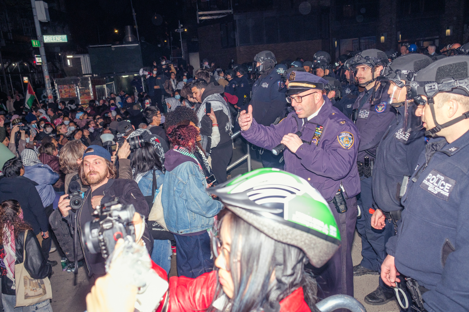 N.Y.P.D. officers stand in a line on Gould Plaza in front of a crowd of pro-Palestinian protesters.