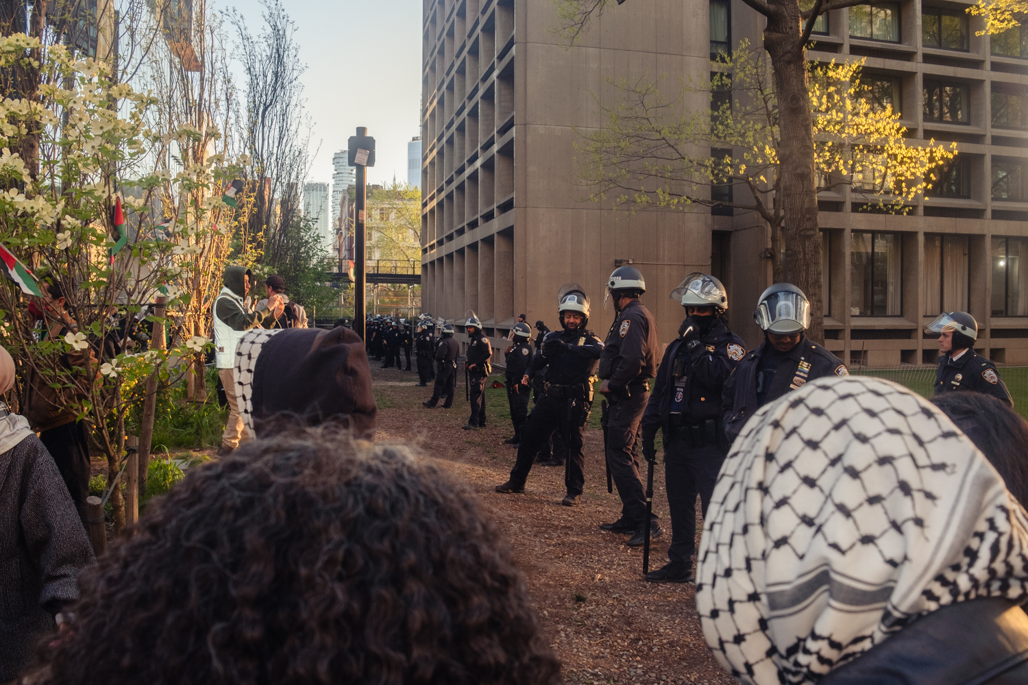 A line of N.Y.P.D. officers stand across protesters on the Greene Street Walkway.
