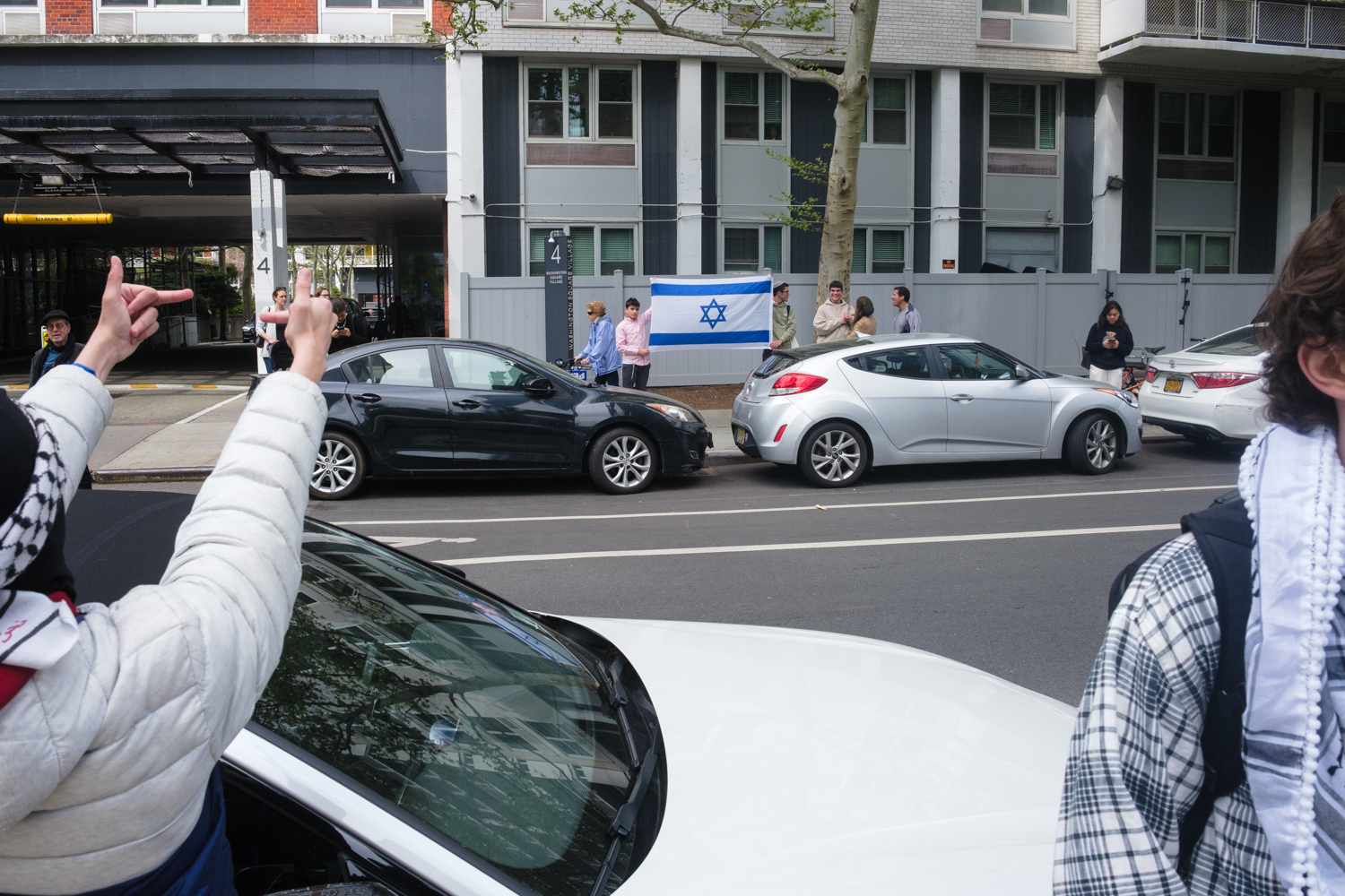 A protester points their middle fingers at pro-Israeli counterprotesters across the street.