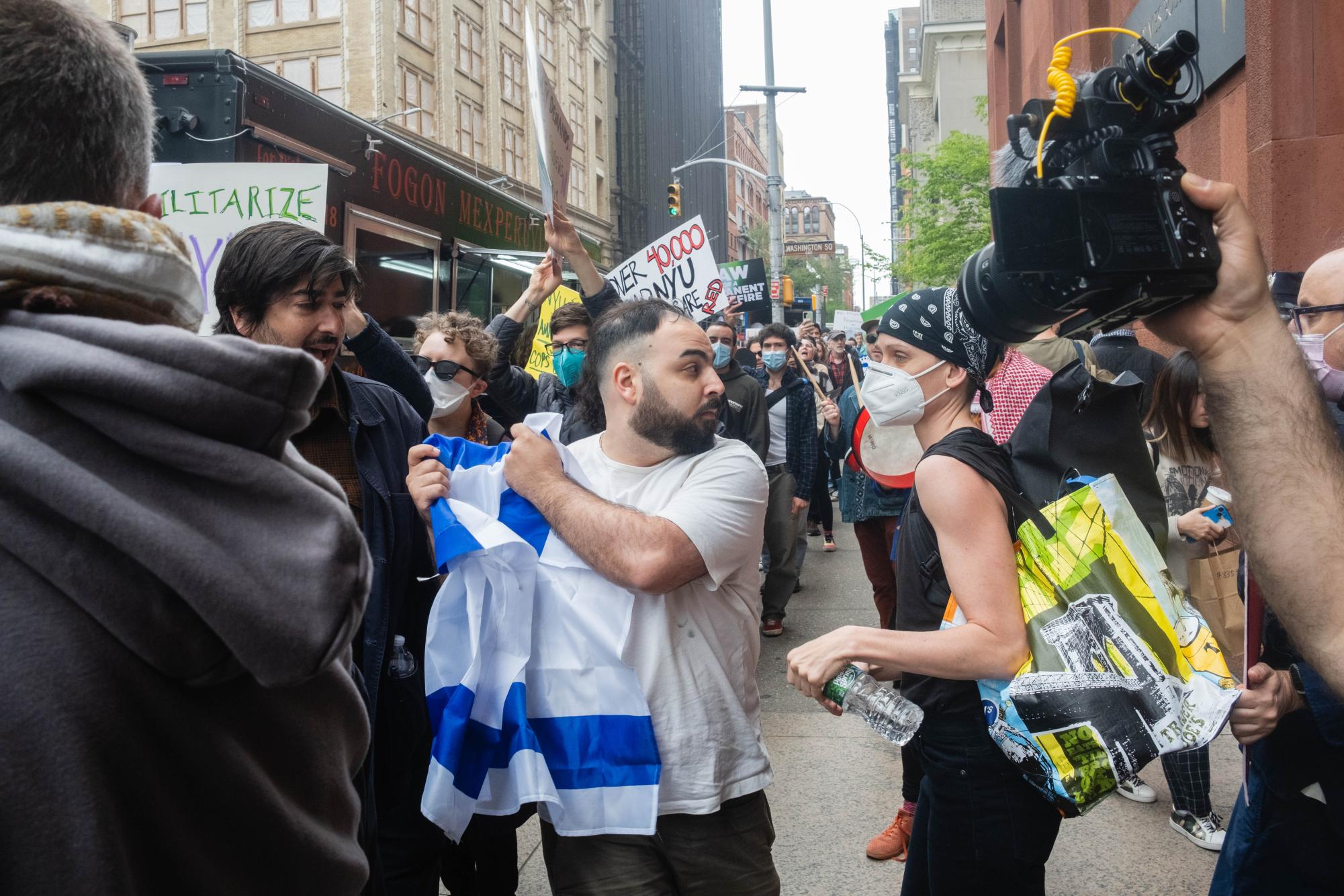A counterprotester holding an Israeli flag confronts a protester in front of Bobst Library.