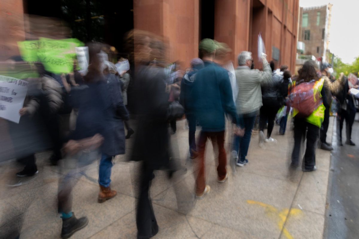 A line of protesters walking on a sidewalk.