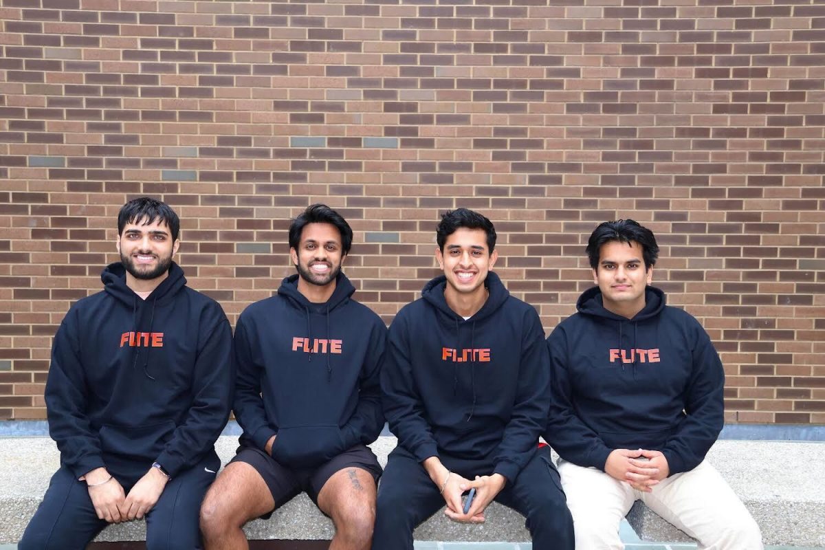 Four men in front of a brick wall in matching black hoodies with “FLITE” written on it.
