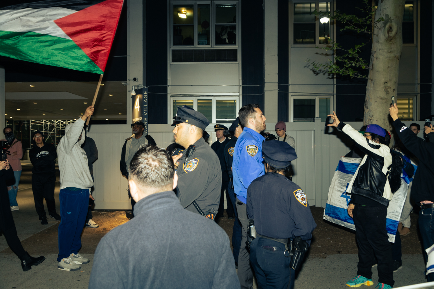 A line of N.Y.P.D. officers form a barrier between pro-Israeli and pro-Palestinian protesters across the street from the encampment.
