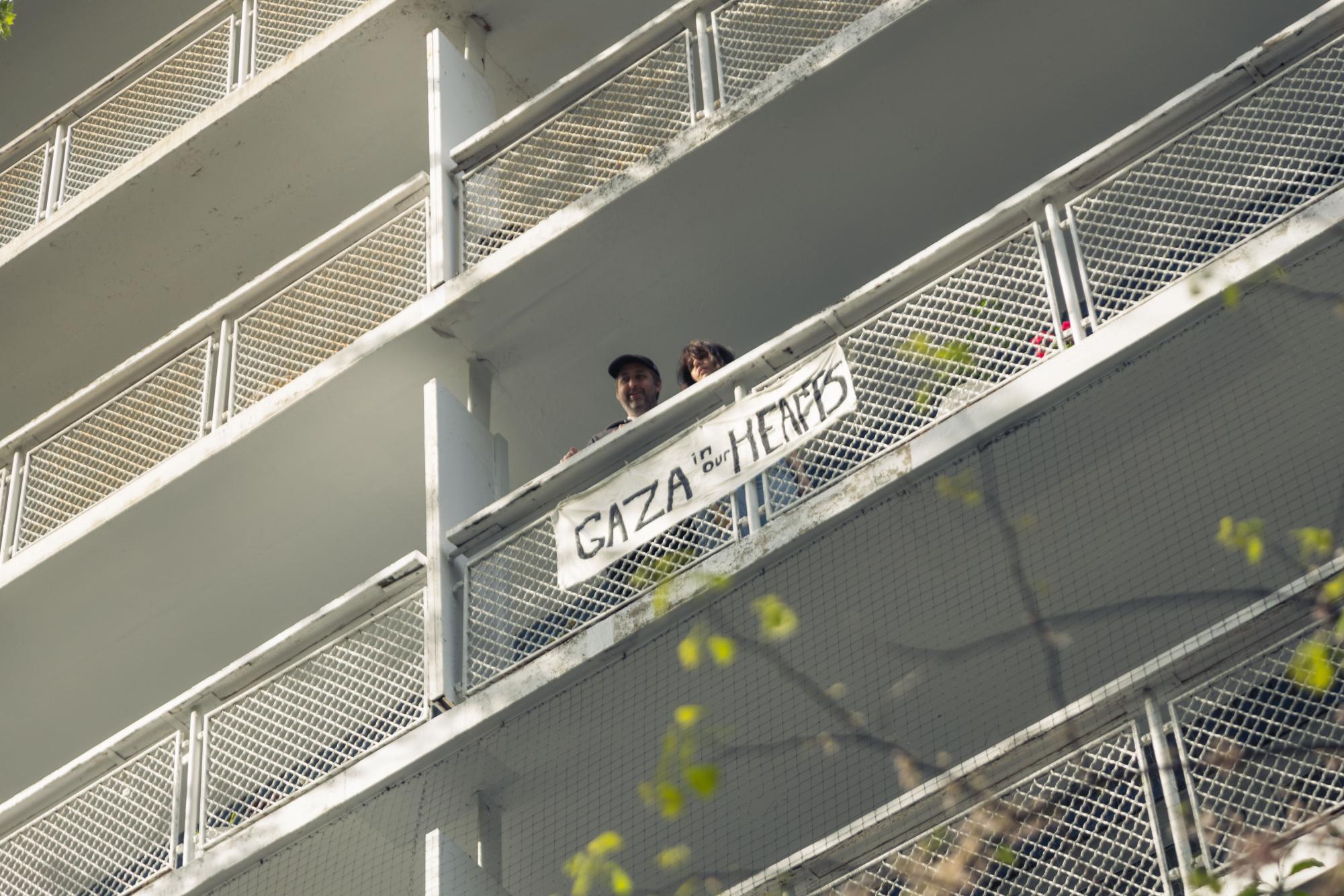 A sign hanging out of a balcony that reads “Gaza in our hearts.”
