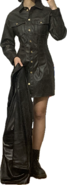 Someone wearing a black leather dress and black shoes, holding a leather jacket.