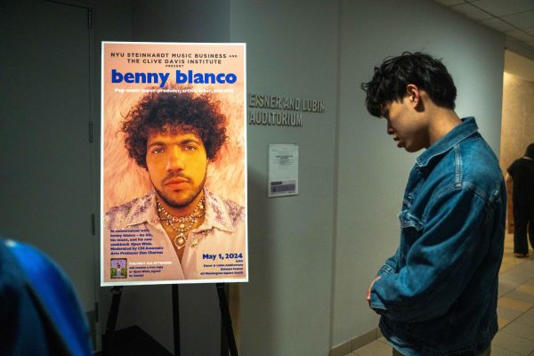 A guest looks at an event poster that displays a headshot of a man and the words “BENNY BLANCO.”