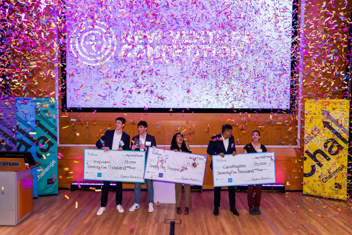 Five people celebrating with confetti holding three large prize checks for $75,000.