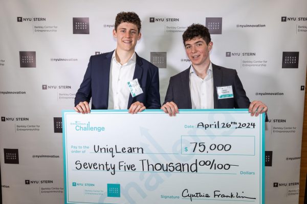 Two men holding up a large prize check for $75,000 from the Entrepreneur’s Challenge.
