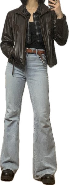 Someone wearing a black tank top, a plaid cropped top, a brown leather jacket, blue jeans and a brown belt.