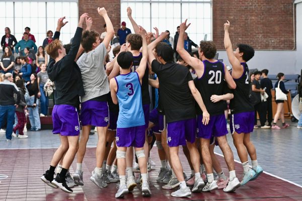The N.Y.U. men’s volleyball team huddles together, jumping with their hands raised.
