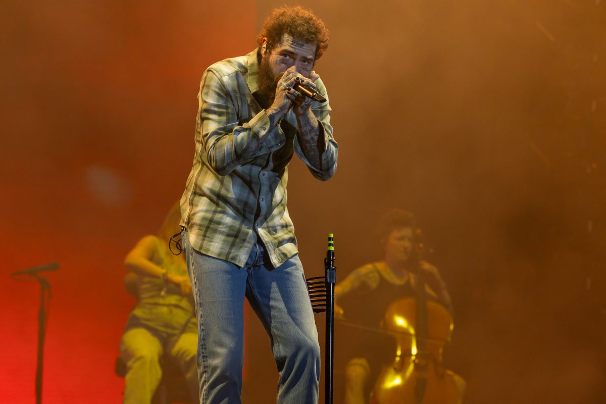 A man wearing flannel holding a microphone to his face.