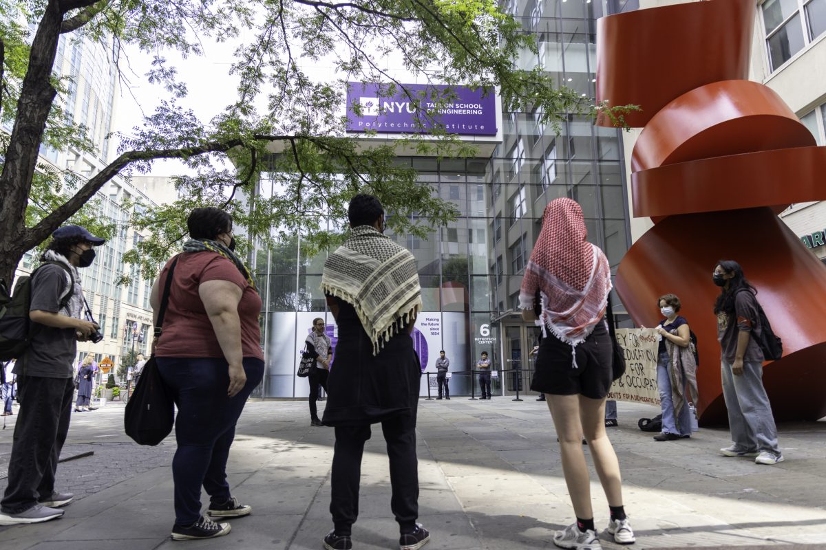 Student protesters stand in front of a building with a sign that reads "NYU TANDON SCHOOL OF ENGINEERING."