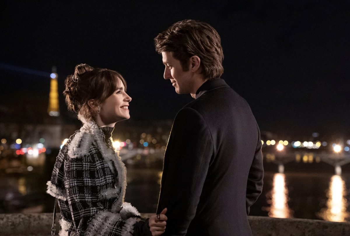 A man and woman look at each other lovingly. In the background is a blurred Eiffel Tower.