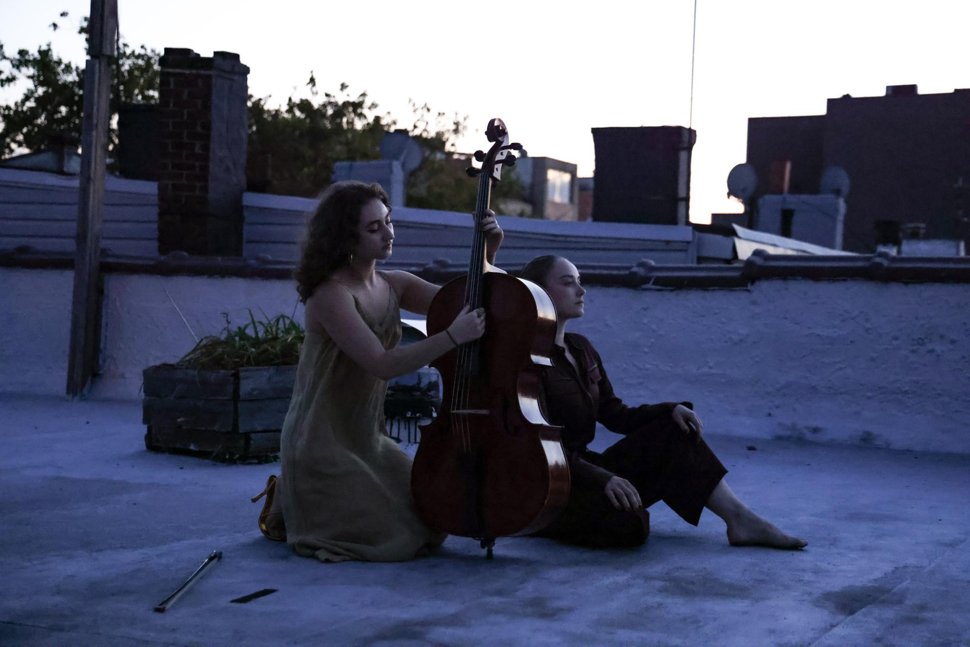 On a rooftop, two people play string instruments.