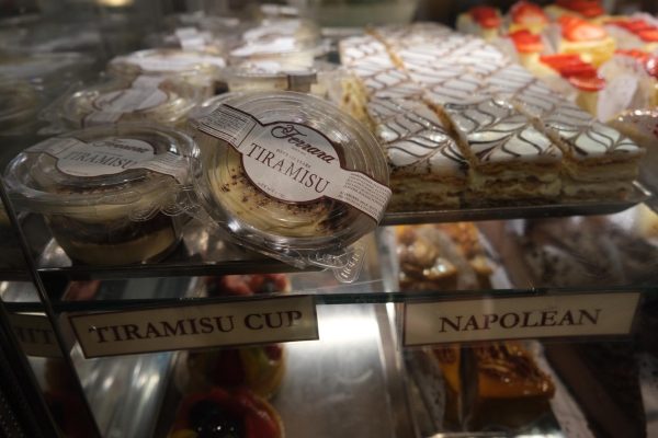 Pastries on display in a glass case with small signs that read “TIRAMISU CUP” and “NAPOLEON”.