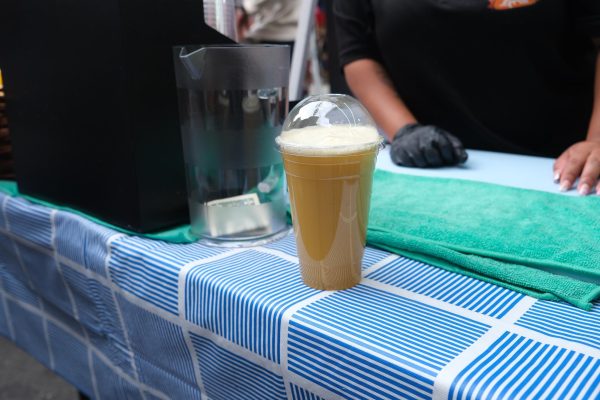 A drink on a blue and white striped tablecloth and a tip jar on the left hand side.