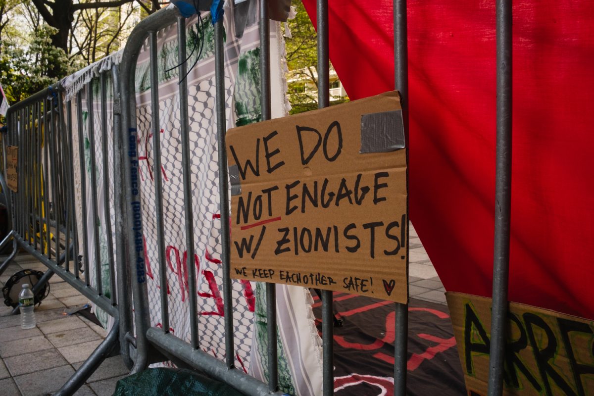 A cardboard sign taped to a metal barricade with the words “WE DO NOT ENGAGE W/ ZIONISTS! WE KEEP EACH OTHER SAFE!”