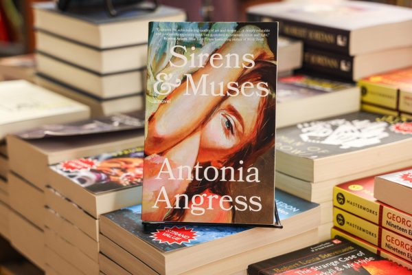 A book with a multicolored cover of a woman’s face with “Sirens & Muses” and “Antonia Angress” written in white.