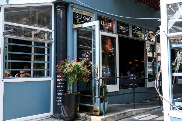 A blue restaurant advertising “BREAKFAST”, “LUNCH”, “DINNER” and “COCKTAILS” with its door open. On the door, it says “DUDLEYS”.