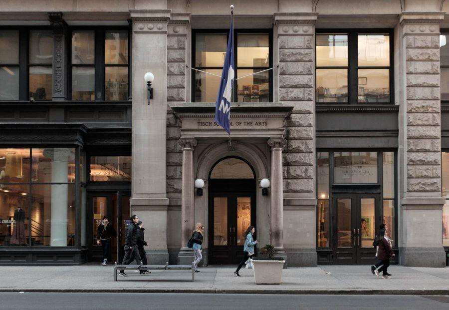 The front of a brown building, with the words "TISCH SCHOOL OF THE ARTS" above the large doors. There are a few people walking down the street in front of the building.